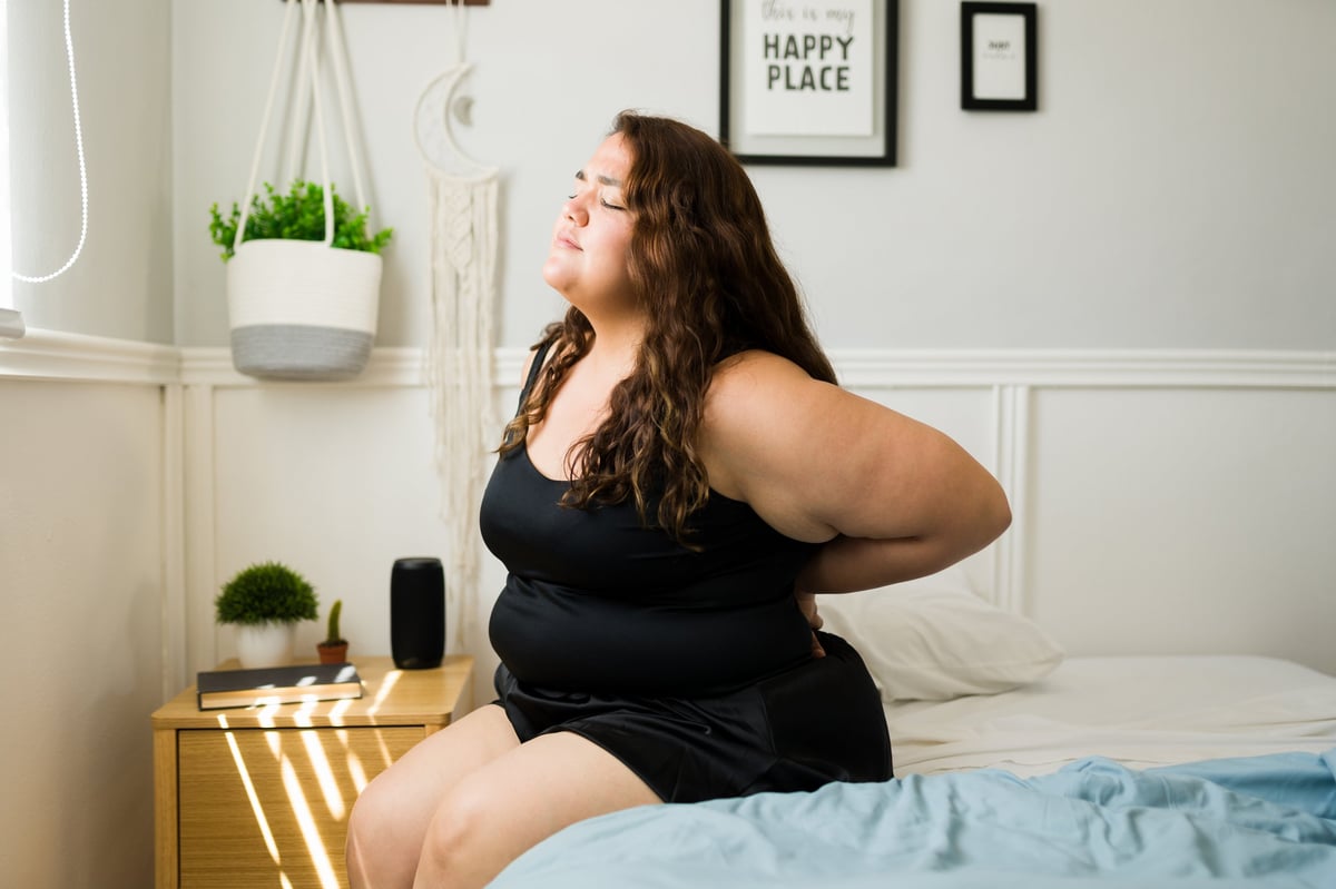 Young woman suffering from back pain, showing impact of weight on spinal health