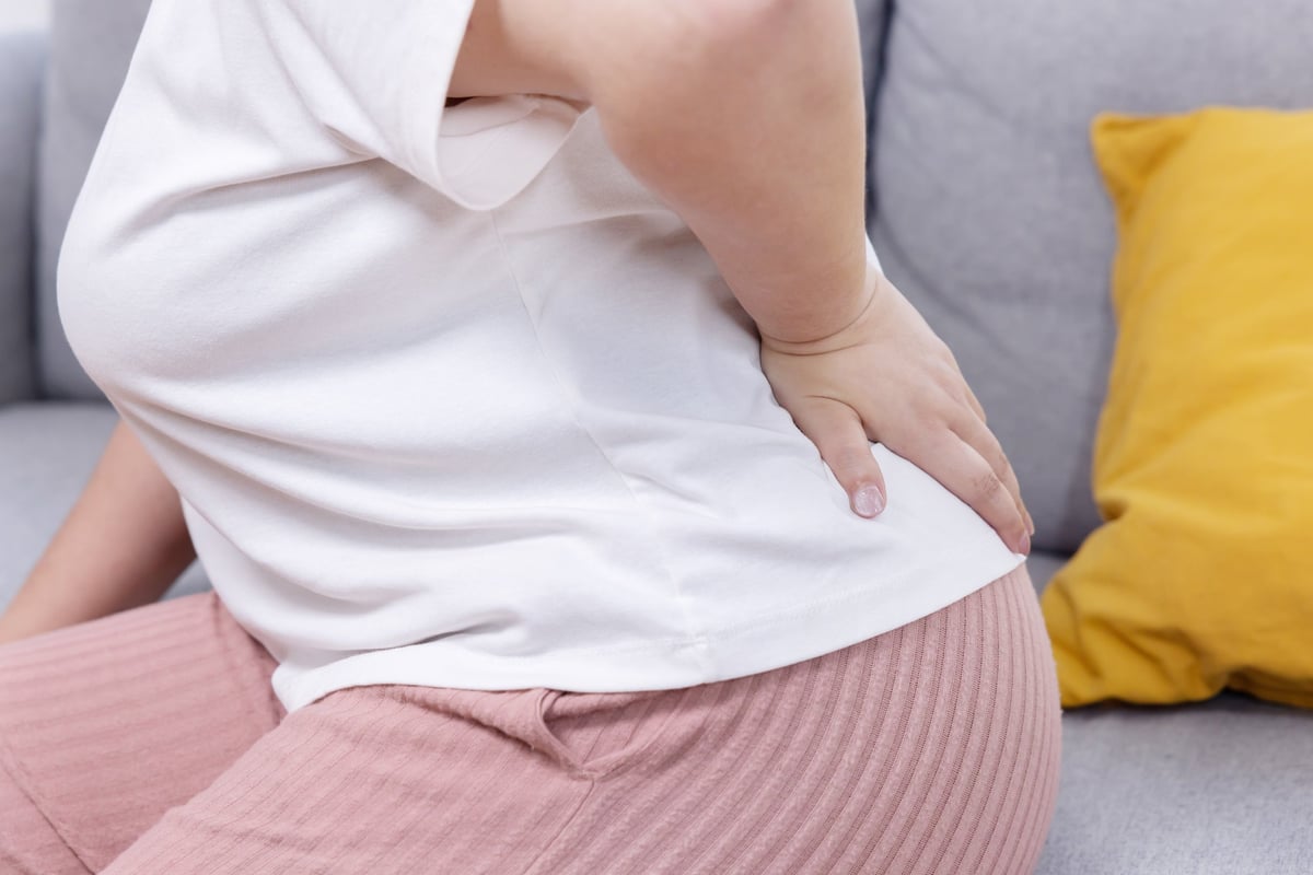 Oversized woman suffering from back pain from excess weight impact on spine