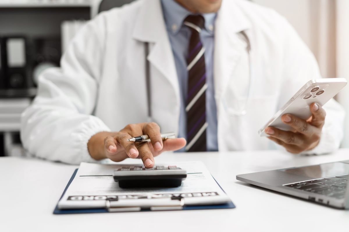 Doctor physician with stethoscope calculate medical fee costs at clinic for spinal surgery price