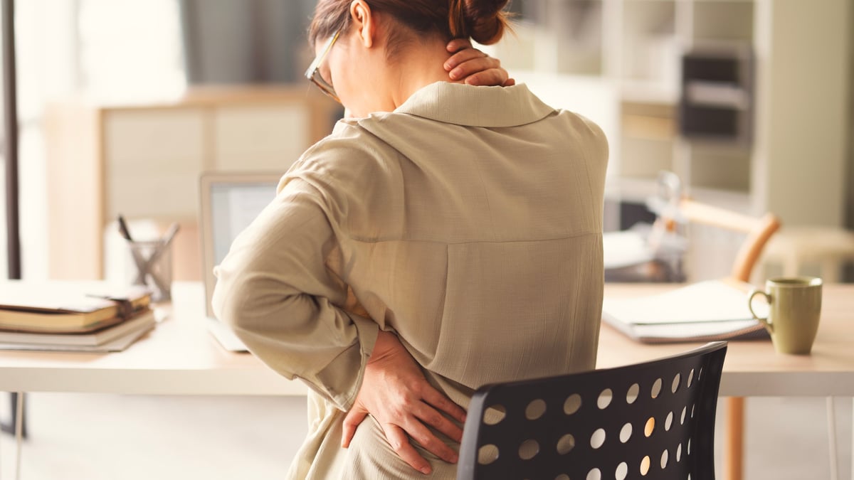 Business woman experiencing back and neck pain from sedentary work