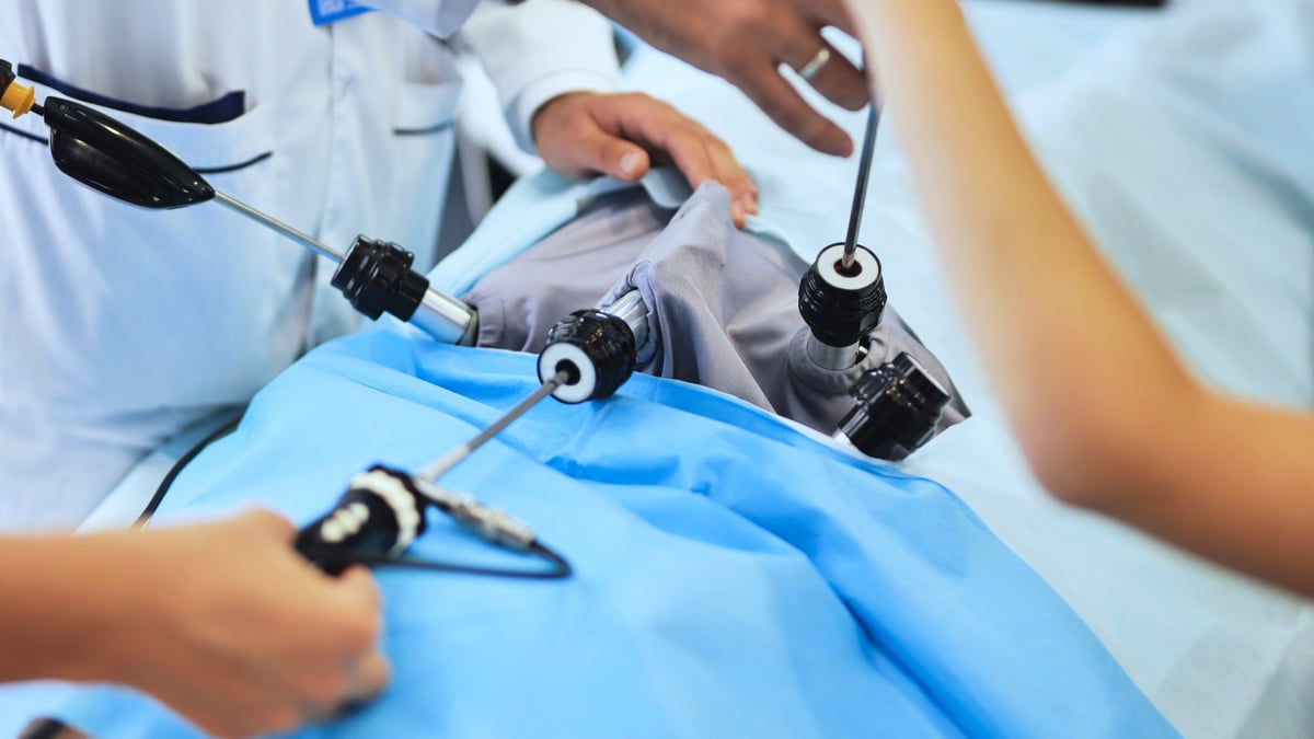 Doctors performing a minimally invasive surgical procedure on a patient in a sterile hospital environment