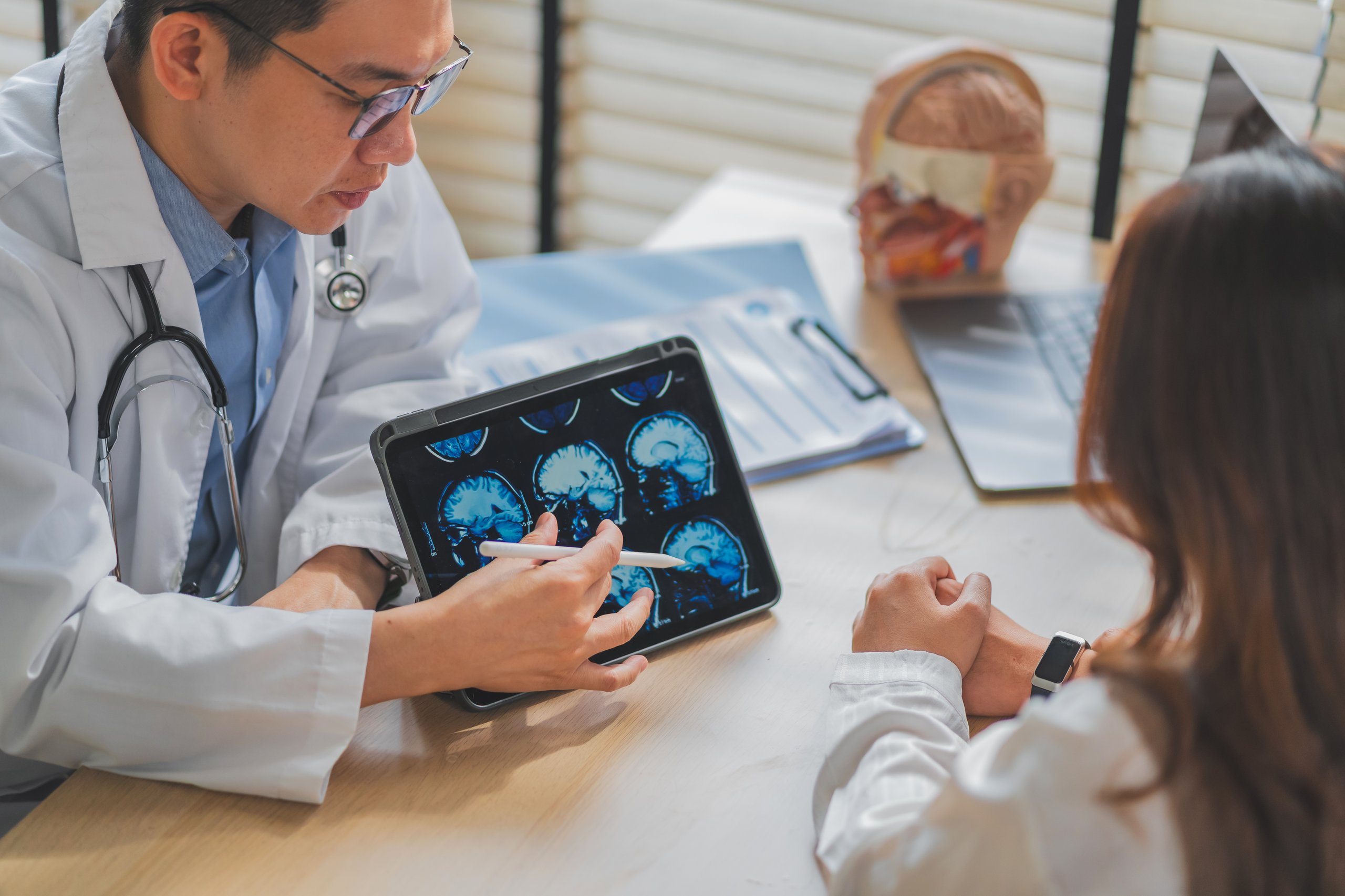 Doctor explicando resonancia cerebral a paciente durante consulta neurológica