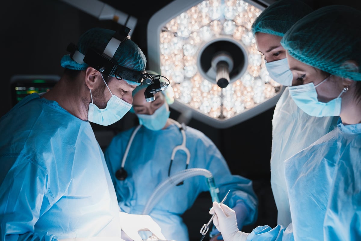 Surgeons performing complex operation in modern operating theater with precise hand movements and surgical instruments under bright lights