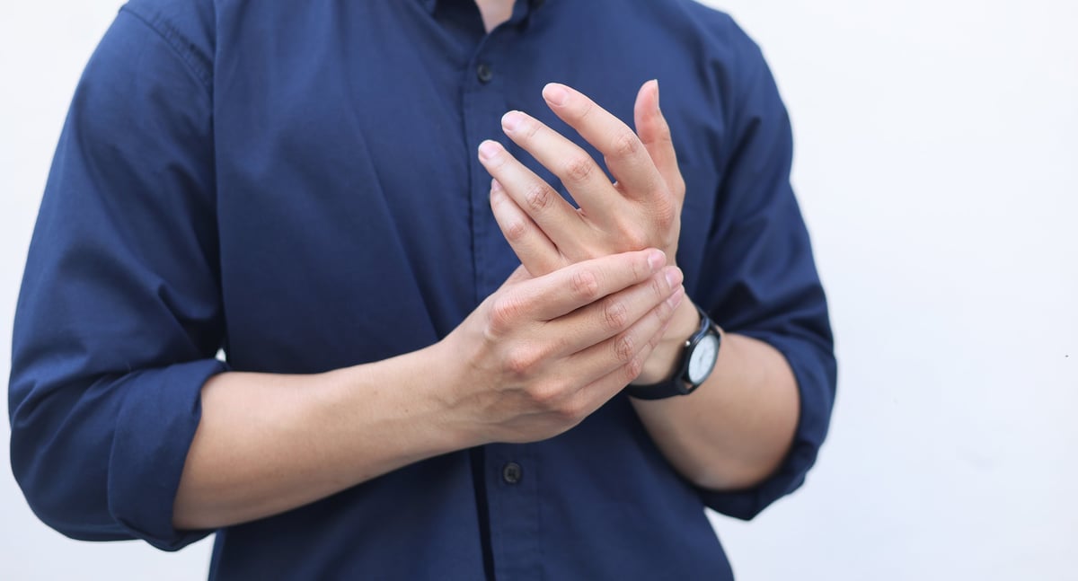 Close up of person massaging hand palm to relieve pain, stiffness or cramp from carpal tunnel or office syndrome